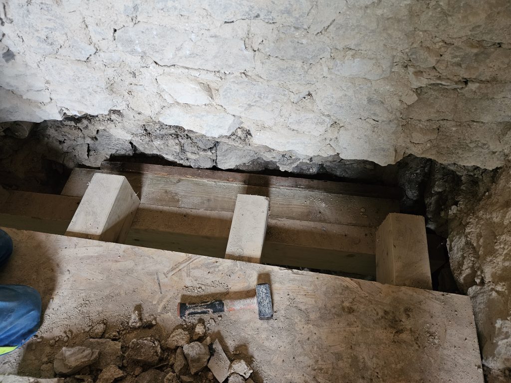 Pose de linteau sous porte sous un mur de pierres