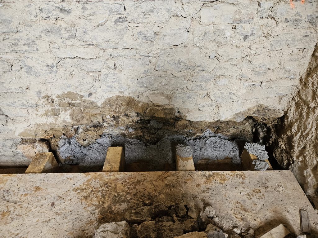 Pose de linteau sous porte sous un mur de pierres