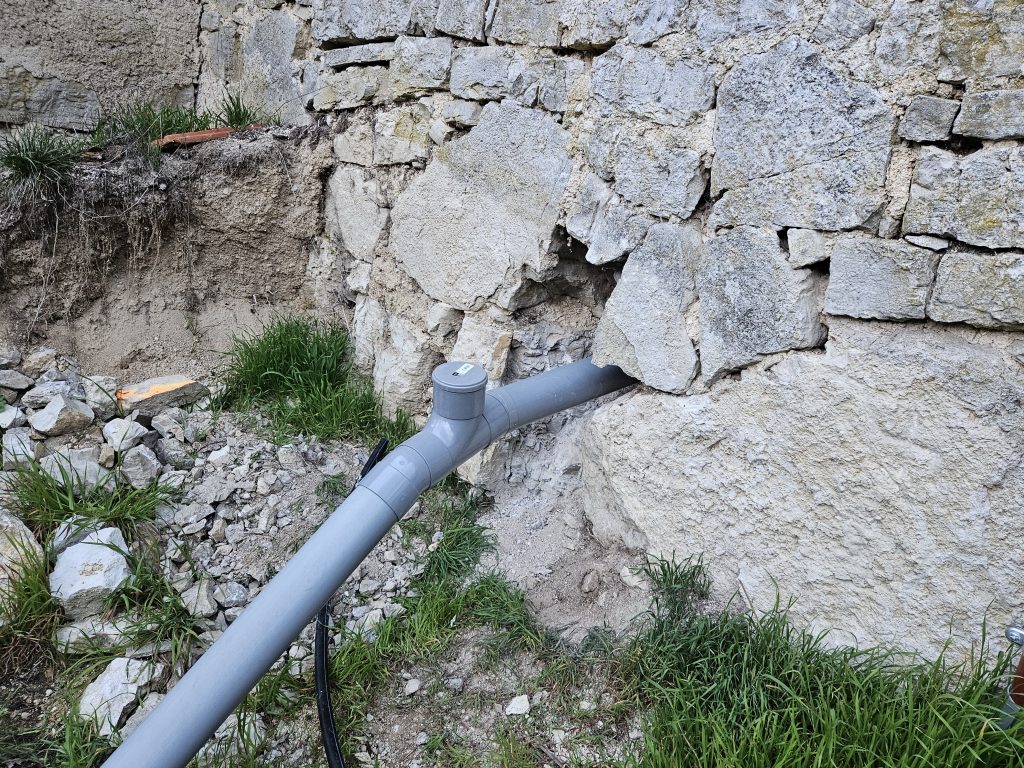 sortie du tuyau des eaux usées au travers d'un mur de pierres de 80 cm
