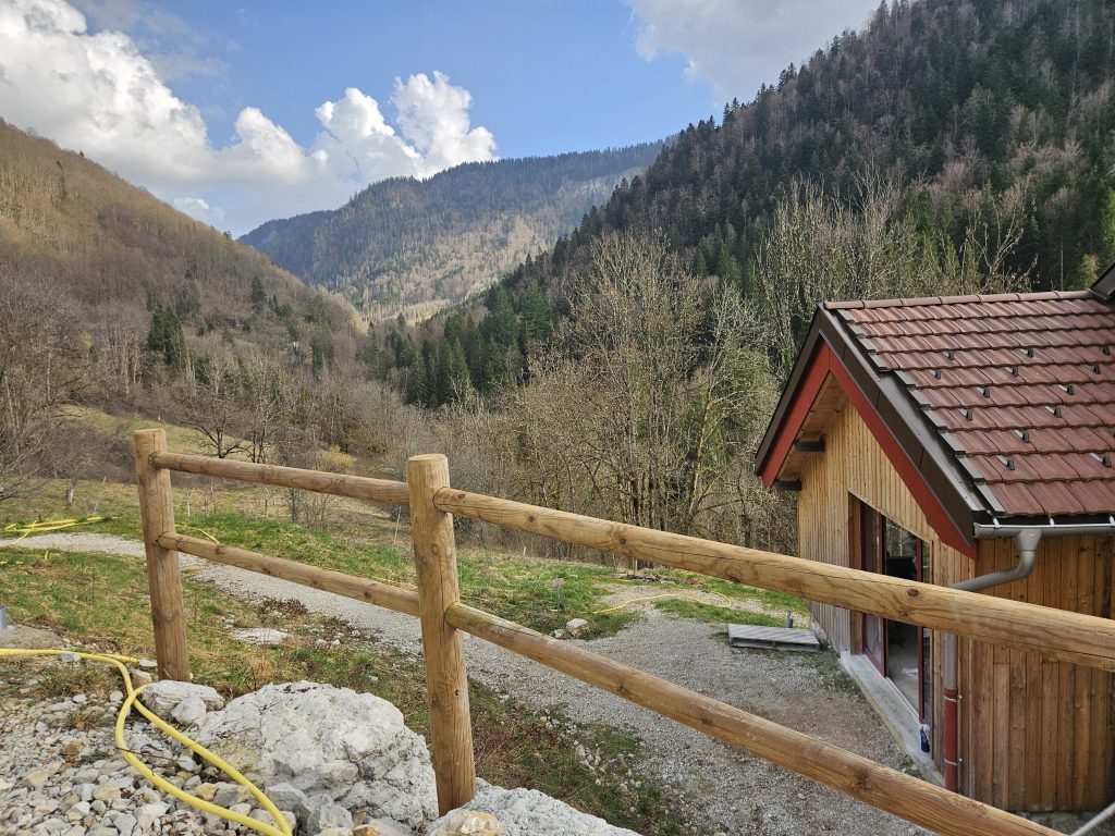 barrière en bois rond avec paysage de montagne dans le jura (gîte)